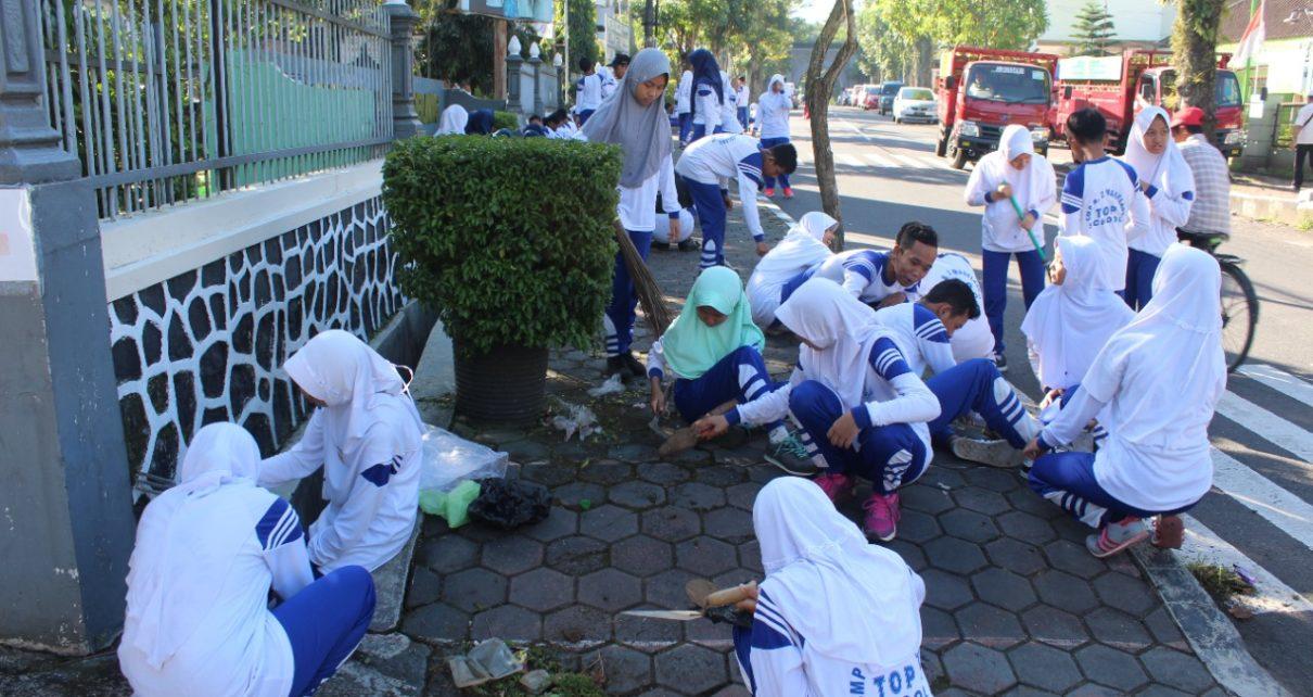 LINGKUNGAN. Peserta didik SMPN 2 Kota Magelang tengah membersihkan lingkungan sekolah. (foto: ist)
